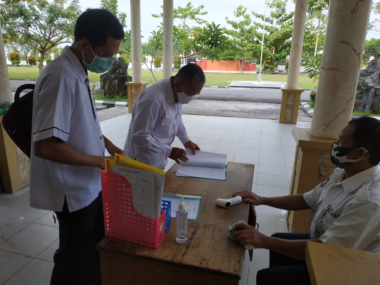 Pegawai melakukan cek suhu sebelum memasuki area kantor
