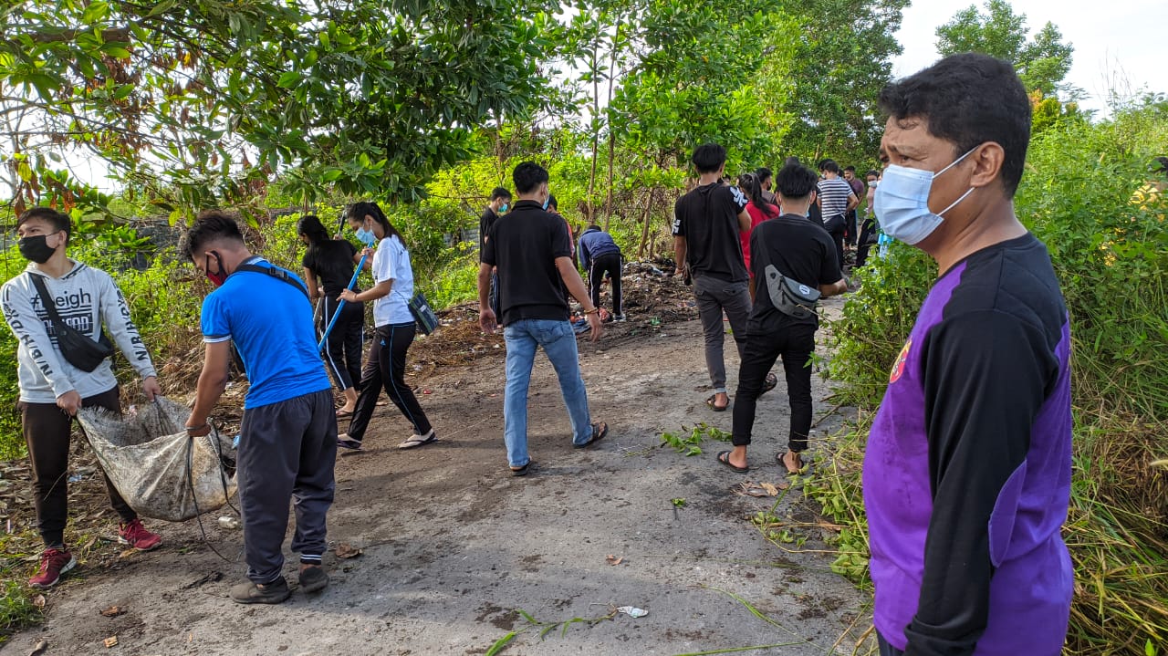 Wakil Rektor III (kanan) bersama mahasiswa melaksanakan aksi membersihkan lingkungan kampus IAHN-TP